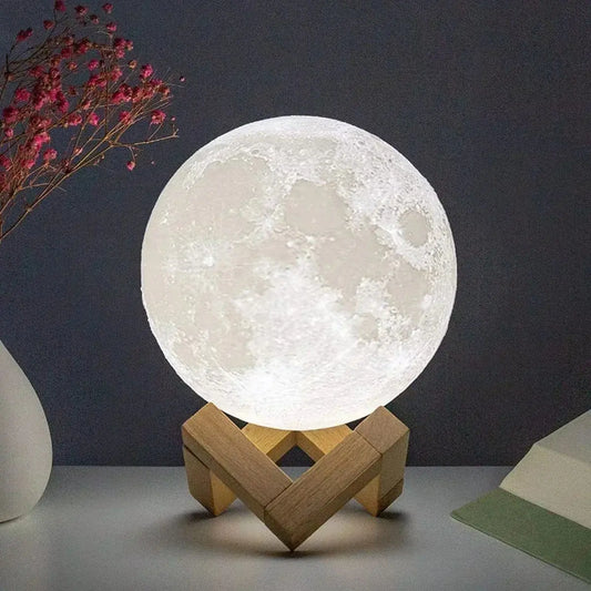 mini 3D moon lamp glowing warm on a small wooden stand beside a bed at night – view 2