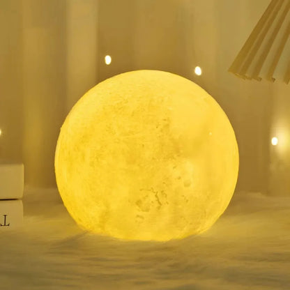 mini 3D moon lamp glowing warm on a small wooden stand beside a bed at night – view 3